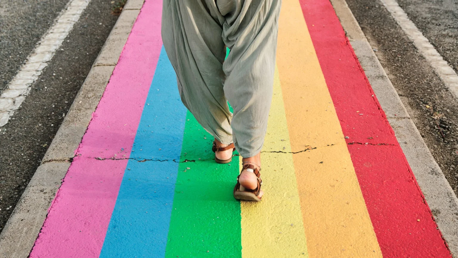 person walking on a street that has the LGBT flag painted on it